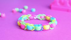 there is a bracelet made out of plastic beads on the pink surface next to it