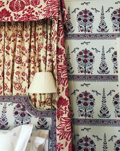 a red and white bed sitting next to a window with curtains on top of it