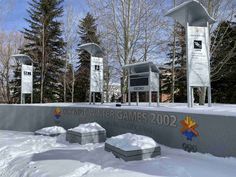 the olympic winter games sign in front of some snow - covered benches and trees with no leaves on them