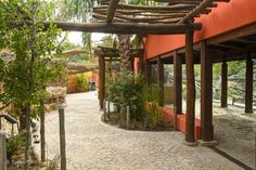 the walkway is lined with wooden poles and plants on either side of the entrance to an orange building