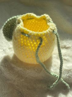 a small crocheted bag sitting on top of a white blanket next to a string