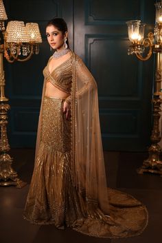 Metallic gold fishcut lehenga with all-over sequin, crystal, and cutdana embroidery with a flowing trail at the back. Paired with a delicate full sleeves blouse with hanging tassel detailing and embroidered dupatta in net.DELIVERY TIMEPlease allow 8-12 weeks for your outfit to arrive.FABRIC DETAILSNetProfessional cleaning only. Gold Embellished Georgette Gown, Gold Floor-length Hand Embellished Anarkali Set, Gold Hand Embellished Floor-length Anarkali Set, Hand Embellished Semi-stitched Pre-draped Saree For Reception, Gold Hand Embellished Gown For Eid, Eid Gold Hand Embellished Gown, Eid Hand Embellished Gold Gown, Gold Georgette Gown For Reception, Anarkali Hand Embellished Saree For Reception