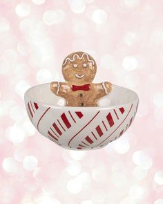 a christmas ornament with a gingerbread man in a bowl on a pink background