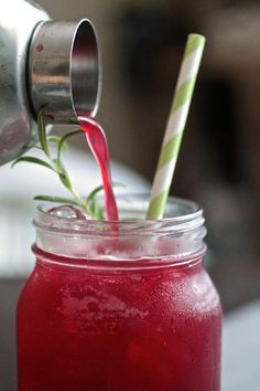 a drink being poured into a mason jar