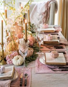 the table is set with candles, books and pumpkins