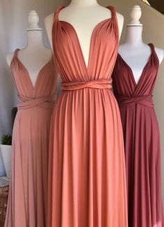 three bridesmaid dresses on mannequins, one in pink and the other in brown