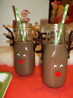 two brown glasses with green and red straws in them on a table next to a stuffed animal