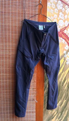 a pair of blue pants hanging up on a wooden wall next to a bamboo mat