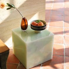 a bowl of fruit and a vase with a flower in it on a marble block