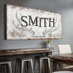 a wooden sign that says smith with antlers on it in front of bar stools