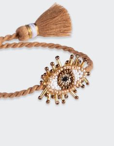 Hand beaded beige Mini Eye Bracelet. Composition: Seed beads, purl wire, leather backing and cotton thread SKU: 2462-0067