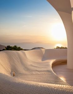 the sun is setting over an outdoor area with white sand dunes and trees in the background