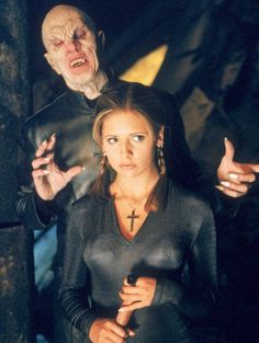 two people dressed in black standing next to each other and one person holding a knife