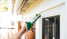 a person is painting the outside of a house with a green paintbrush and glue