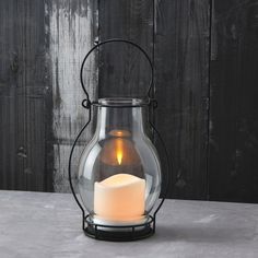 a lit candle in a glass container on a table