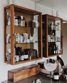 two wooden medicine cabinets filled with personal care items on top of a counter next to a mirror