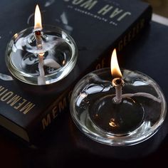 two lit candles sitting on top of a book