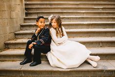 two children sitting on steps in formal dress