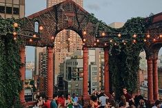 many people are sitting at tables on top of a building with vines growing up the roof