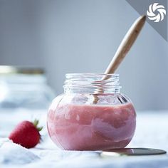 a jar filled with baby food next to a strawberries on top of a table