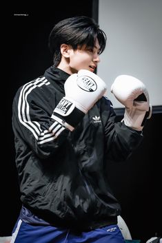 a young man with black hair wearing white boxing gloves and holding a white glove in his right hand