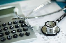 a stethoscope sitting on top of a calculator next to a pair of glasses