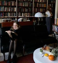 a woman sitting on a couch in front of a bookshelf filled with books