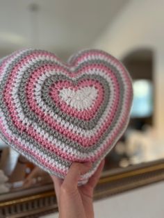 someone holding up a crocheted heart in front of a mirror