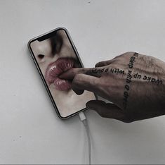 a person with their hand on top of a cell phone that has an image of a woman's face and words written on it