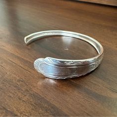 a silver bracelet sitting on top of a wooden table