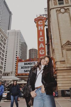 a woman standing in front of the chicago theatre with her hand on her hip and looking at the camera