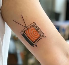 a person with a tattoo on their arm that has an orange tv on it and arrows coming out of the screen