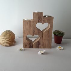 a wooden block with two hearts cut out of it next to a shell and flower pot