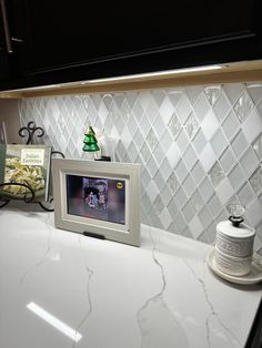 a kitchen counter with a white tile backsplash and an old fashioned tv on it