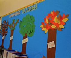 a classroom wall decorated with trees and fall leaves for the seasons's greetings