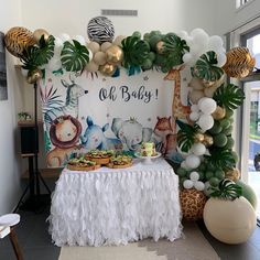 a baby shower with jungle animals, balloons and desserts on a table in front of a backdrop