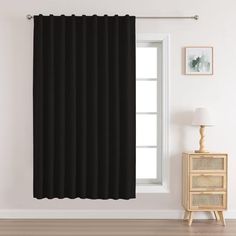 a black curtain hanging on the side of a white wall next to a wooden table