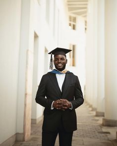 a man in a graduation cap and gown is standing on the sidewalk with his hands in his pockets