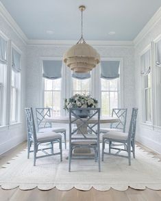 a dining room table with four chairs and a chandelier hanging from the ceiling