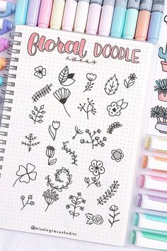 a notebook with flowers and plants drawn on it next to crayons, pens and markers