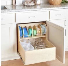 an open drawer in a kitchen filled with dishes