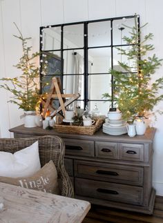 a mirror sitting on top of a dresser next to a table with christmas trees in it