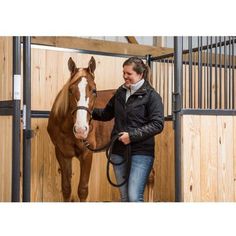 a woman is leading a horse in an enclosed area