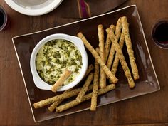 a plate topped with cheesy bread sticks next to a bowl filled with dip