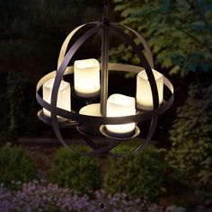 an outdoor chandelier with lit candles in the shape of circles hanging from it's center