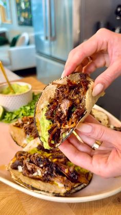 a person is eating a sandwich on a plate with guacamole in the background