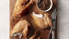 a wooden cutting board topped with chicken legs and sauce