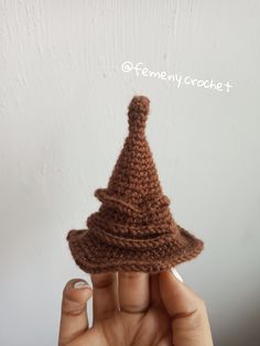 a hand holding a crocheted brown hat