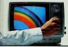 a person's hand on top of an old television with a rainbow painted on the screen