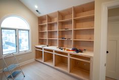 an empty room with wooden shelves and toys on the floor in front of a window